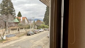A view from inside a building looking out onto a street with parked cars and trees. - ROLANDO BEDS Bariloche (San Carlos de Bariloche)