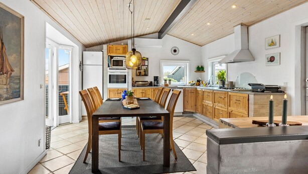 A spacious kitchen with wooden cabinets, a dining area with a large table and chairs, and a modern pendant light. - Cozy home in Otterup with WiFi (Otterup)