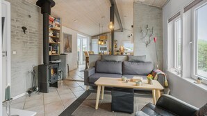 A cozy living room with a fireplace, a sofa, a table with a mug, and a bookshelf. - Cozy home in Otterup with WiFi (Otterup)