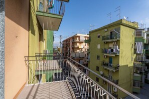 Un immeuble résidentiel à plusieurs étages, doté de balcons, d’une façade verdoyante et surplombant un ciel dégagé.