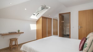A bedroom with a skylight, wooden wardrobe, and a small stool. - Vacations in Funchal, sea view - Casa Strelitzia II (Funchal)