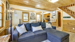 A modern living room with a sectional sofa, a wooden ceiling, and a staircase leading to another level. - Sugarloaf Vacation Rental ~ 7 Mi to Big Bear Lake! (Sugarloaf)