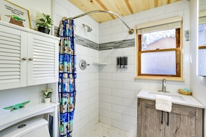 Een badkamer met een douche, een wastafel en een raam.