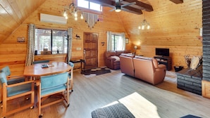 A cozy cabin interior with a dining table, sofa, and fireplace. - Decks + Fire Pit: Rustic-Modern Overgaard Cabin! (Overgaard)