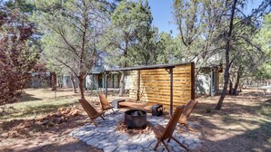 An outdoor patio with stone flooring, wooden furniture, and a fire pit. - Decks + Fire Pit: Rustic-Modern Overgaard Cabin! (Overgaard)