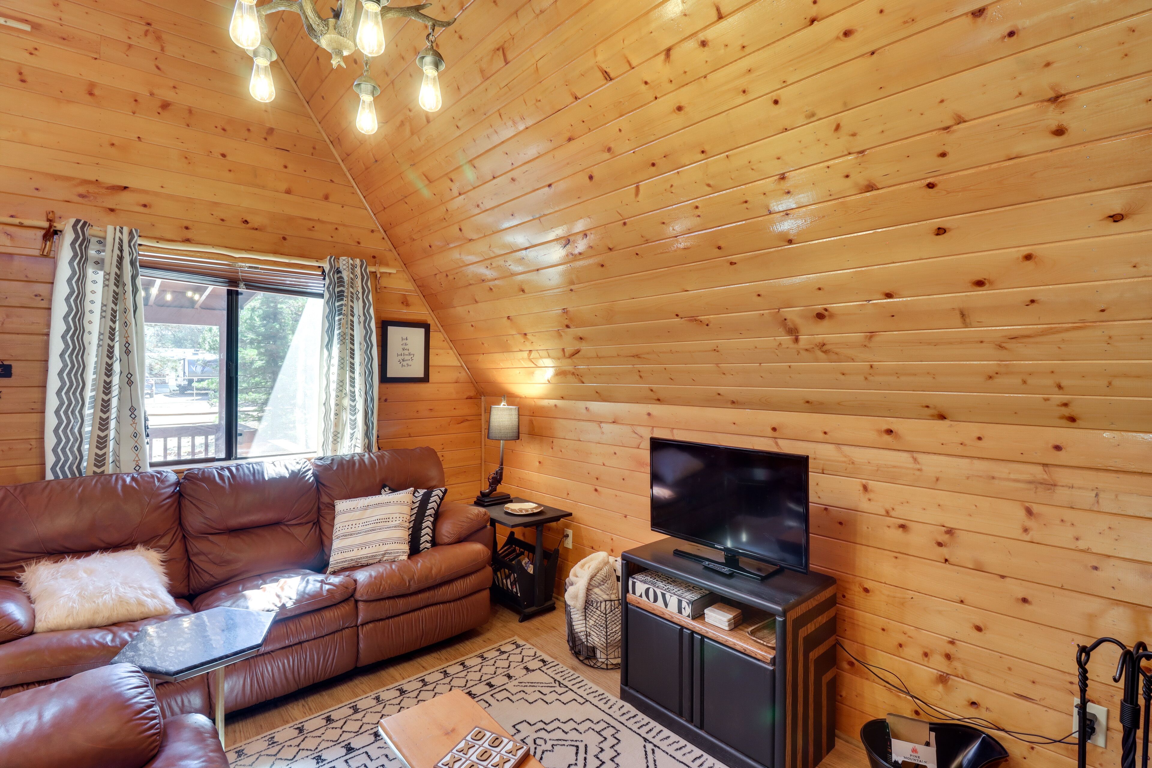 L’intérieur d’un chalet en bois chaleureux et accueillant, avec un canapé en cuir, un téléviseur et une cheminée.