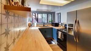 A modern kitchen with a wooden countertop, a stainless steel refrigerator, and a black stove. - Decks + Fire Pit: Rustic-Modern Overgaard Cabin! (Overgaard)