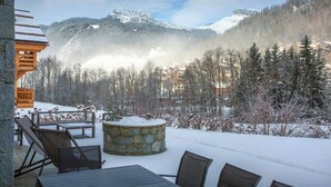 Ein mit Schnee bedeckter Außenbereich mit Steinsäulen und Blick auf schneebedeckte Berge.