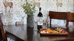 Un tavolo di legno con una bottiglia di vino, due bicchieri e un tagliere di salumi.