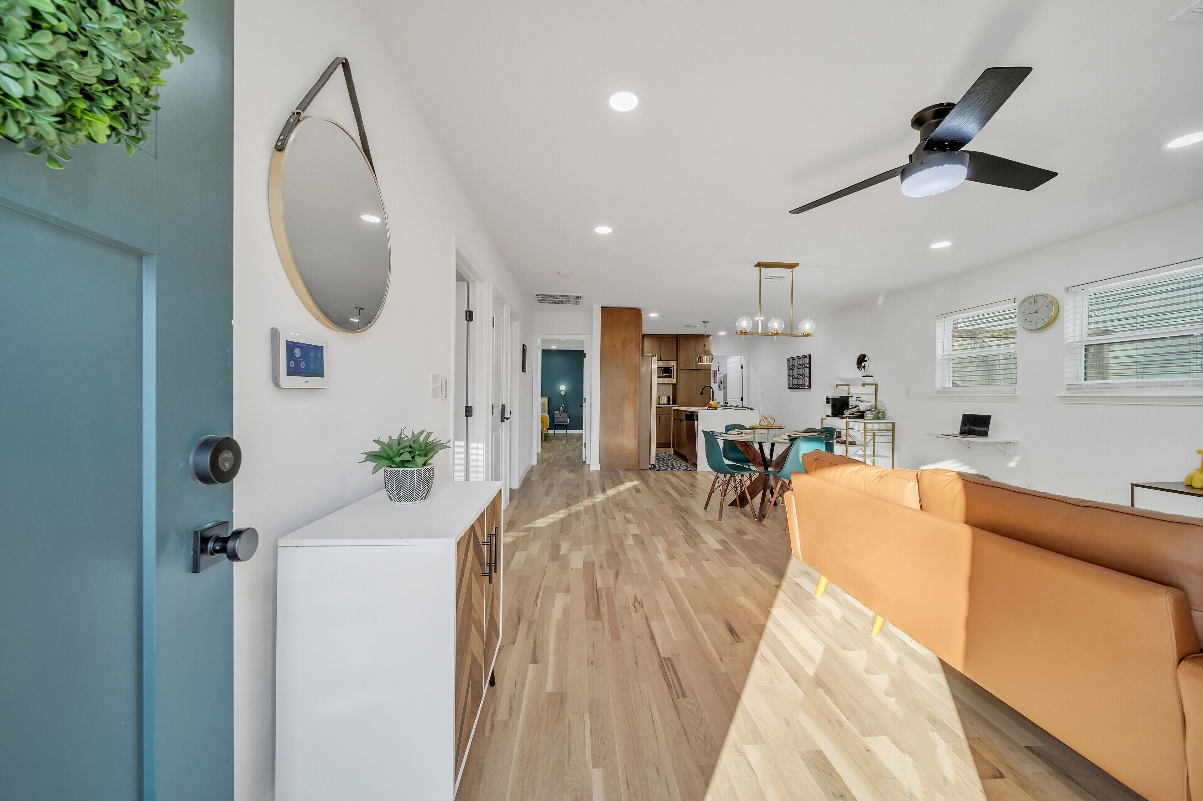 A modern kitchen with a dining area, a ceiling fan, and a large mirror.