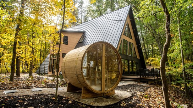 A cabin with a unique barrel-shaped structure in a forest setting. - Modern Aframe with River Views, Sauna, Hot Tub (Fennville)