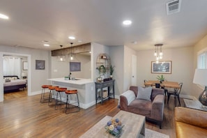 A modern living room with a sofa, coffee table, and a dining area with a table and chairs. - Modern Stay | 10 Min Walk From AT&T Stadium (Arlington)