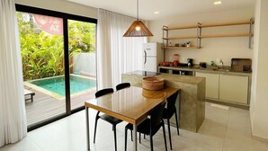 A modern kitchen with a dining area, a large window, and a view of a swimming pool.