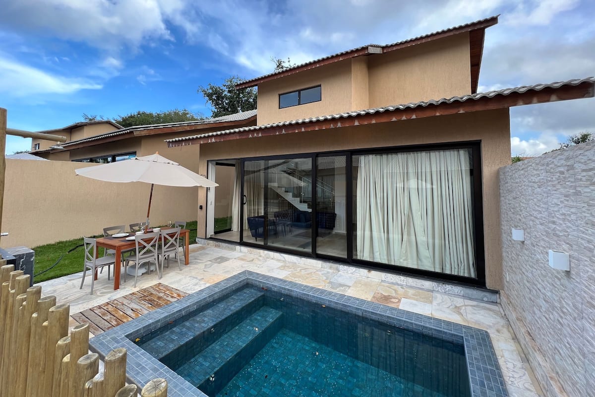 Ein modernes Haus mit Swimmingpool, einer Terrasse und Gartenmöbeln sowie einem großen Schiebe-Glasfenster.