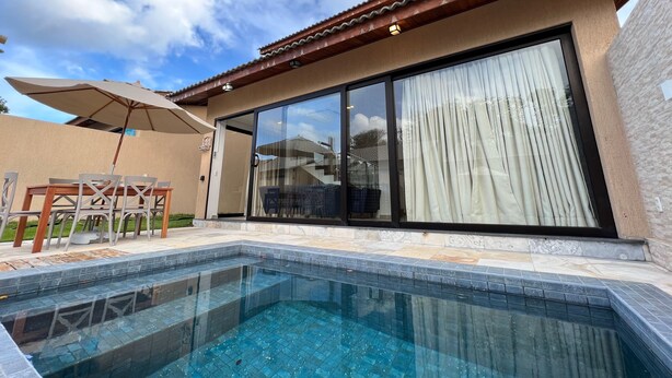 A modern house with a swimming pool, large sliding glass doors, and a patio with outdoor furniture.
