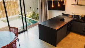 A modern kitchen with a large island, a dining area with a table and chairs, and a view of a swimming pool.