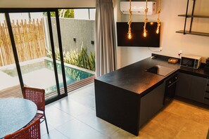 A modern kitchen with a large island, a dining area with a table and chairs, and a view of a swimming pool.