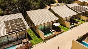 A modern resort with multiple villas featuring solar panels, outdoor pools, and lush greenery.