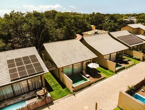 A modern resort with multiple villas featuring solar panels, outdoor pools, and lush greenery.