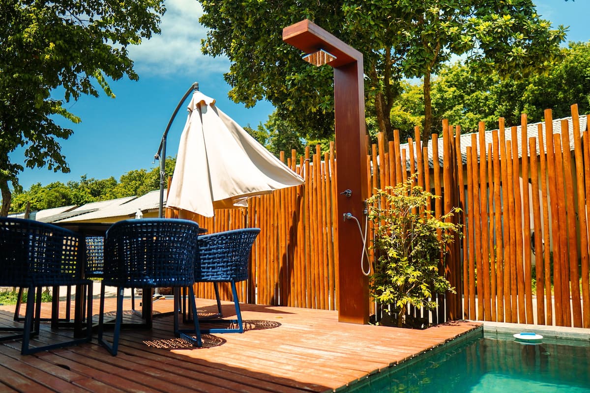 Eine Holzterrasse mit Pool, Bambuszaun und Gartenmöbeln.