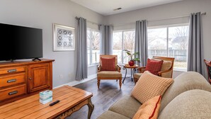 A living room with a TV, wooden furniture, a sofa, and a chair. - Spacious 4BR - King Bed - Near I-70 (Dayton)