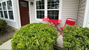 A house with a front porch, a red door, and two red chairs. - Spacious 4BR - King Bed - Near I-70 (Dayton)