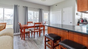 A modern kitchen with a large island, wooden cabinets, and a dining area with a table and chairs. - Spacious 4BR - King Bed - Near I-70 (Dayton)
