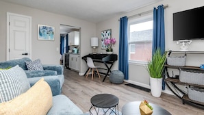A modern living room with a sofa, coffee table, and a dining area with a table and chairs. - Remodeled-Pet friendly-5 min to WPAFB and Downtown (Dayton)
