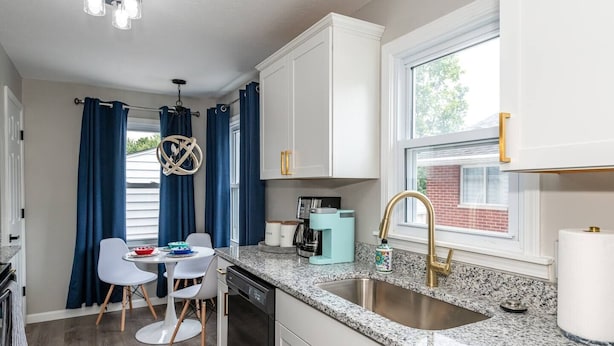 A modern kitchen with white cabinets, a granite countertop, a stainless steel sink, and a coffee machine. - Remodeled-Pet friendly-5 min to WPAFB and Downtown (Dayton)