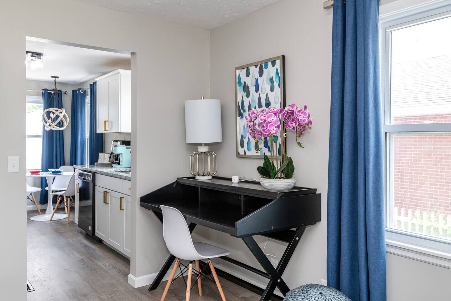 Een moderne keuken met witte kastjes, een zwarte aanrecht en een eethoek met een witte tafel en stoelen.