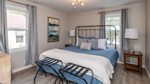 A bedroom with a bed, two bedside tables with lamps, a window with curtains, a wall-mounted picture, and a ceiling light fixture. - Remodeled-Pet friendly-5 min to WPAFB and Downtown (Dayton)