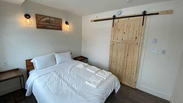 Un dormitorio con una cama, mesitas de noche, un armario de madera y un aplique de pared.
