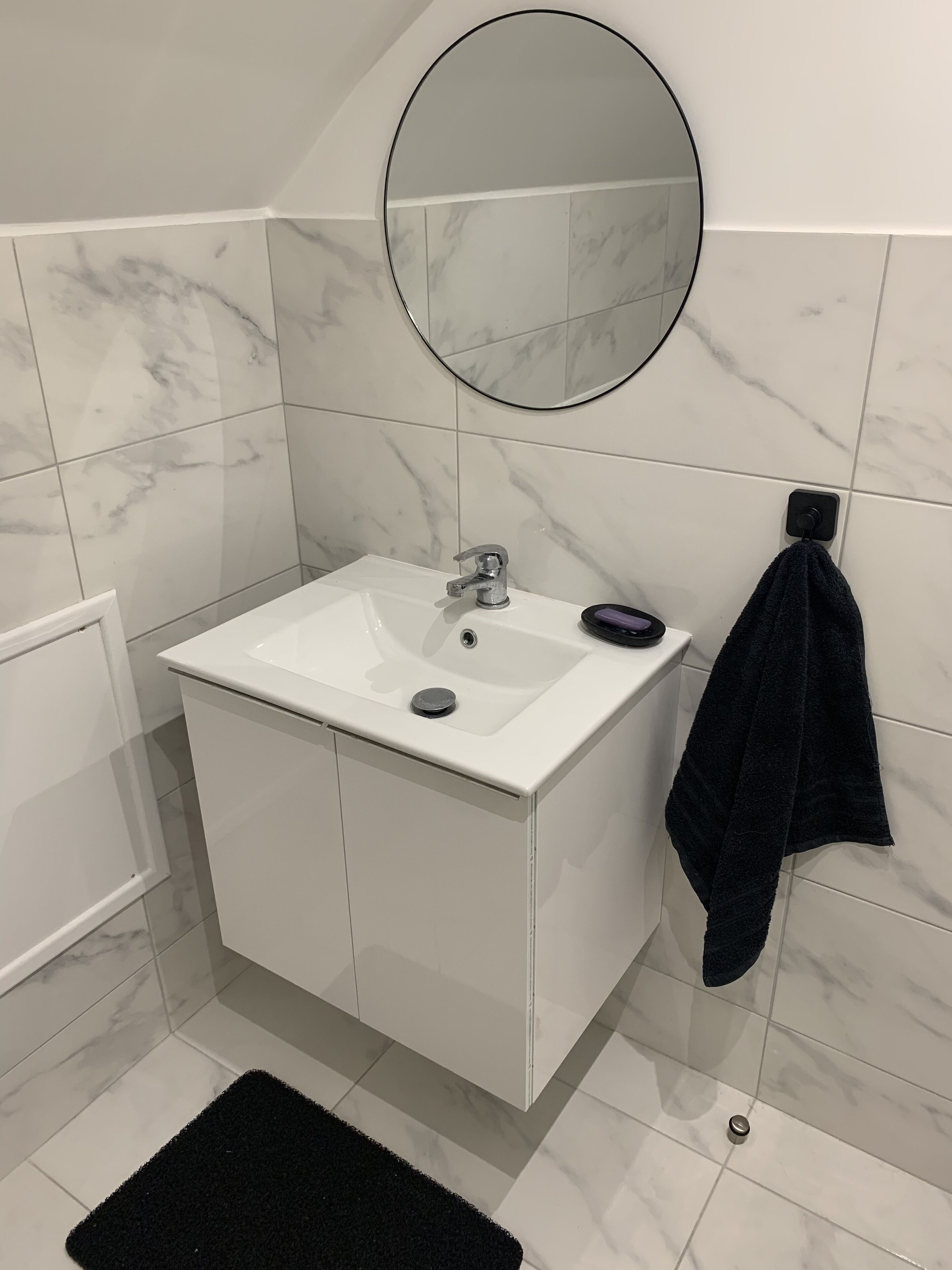 A bathroom with a white sink, a mirror, and a towel rack.
