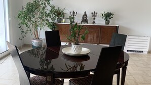 Un coin repas avec une table ronde, quatre chaises et une plante en pot.
