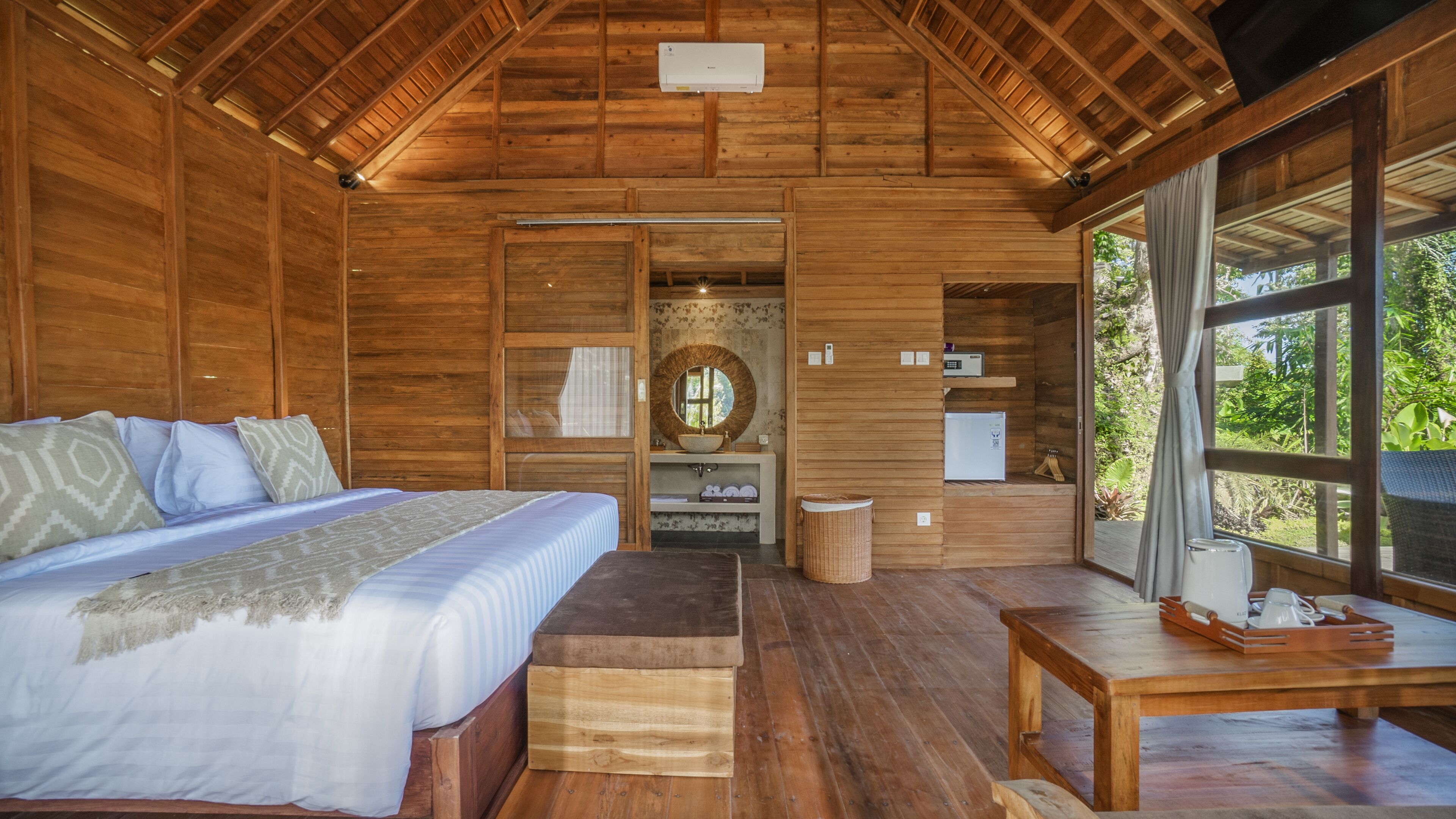 Una cabaña de madera con una cama, una mesita y una ventana.