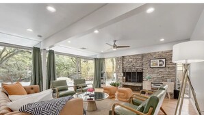 Un salon spacieux doté d’une cheminée en pierre, de sièges confortables et de grandes fenêtres.