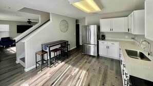 Eine moderne Küche mit weißen Schränken, einem Edelstahlkühlschrank und einer Bar mit Sitzgelegenheiten.
