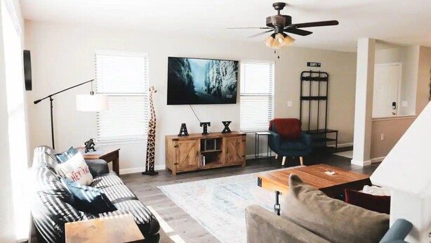 Ein modernes Wohnzimmer mit einer Couch, einem Couchtisch und einem an der Wand montierten Fernseher.