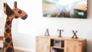 Eine Giraffenfigur in einem Raum mit Fernseher und Holzschrank.