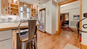 Una cocina moderna con armarios de madera, un refrigerador de acero inoxidable y un comedor con una silla y una mesa.