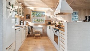 Eine kompakte Küche mit Holzausstattung, einer zentralen Kücheninsel und einem großen Fenster für natürliches Licht.