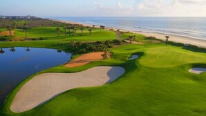 Ein Golfplatz mit Sandbunkern, einer Wasserfalle und einem Strand im Hintergrund.