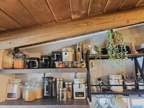 A kitchen shelf with various food storage containers, a hanging plant, and kitchenware. - Secluded log cabin/hot tub. Ski, views, hike, silence. (Black Hawk)