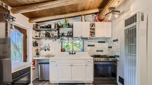 Eine moderne Küche mit weißen Schränken, einem Edelstahl-Kühlschrank, einem eingebauten Backofen und einem Gasherd.