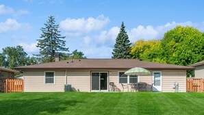 A single-story house with a front door, sliding glass windows, and a patio area with a table and chairs. - Single Family home in Schaumburg, IL 3 bed/ 2 full baths/ fully fenced backyard (Schaumburg)