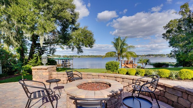 Un patio con mobili da esterno, un braciere e vista su un lago.