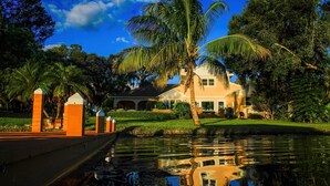 Una proprietà sul lungomare con una casa, palme e un canale.