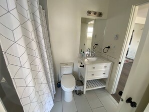 Bathroom features a toilet, sink, and shower with a geometric patterned curtain.