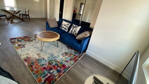 A living room with a blue sofa, a wooden coffee table, and a colorful rug. - Historical Building 1br 1ba Walk To Roger's Place (Edmonton)