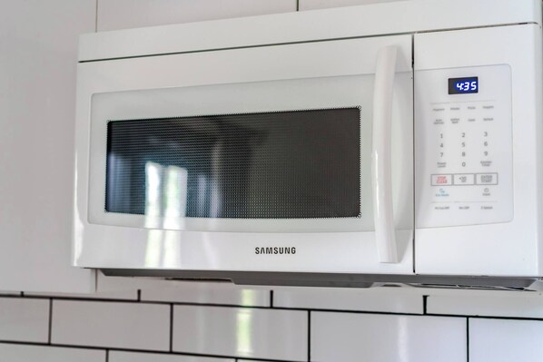 A white Samsung microwave oven with a digital display and control panel.